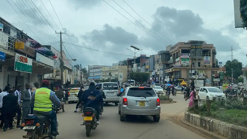 The main high street in Mbarara City with shopfronts, traffic and pedestrians